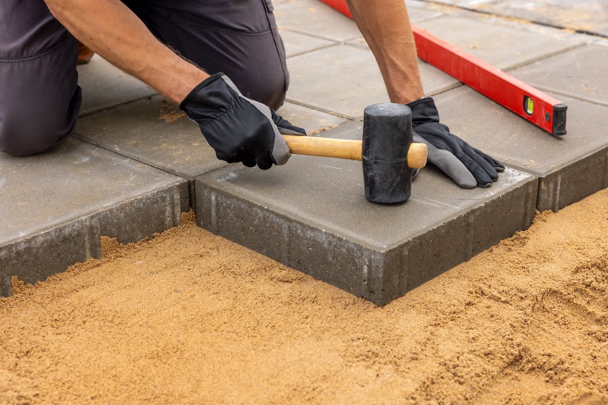 Worker installing concrete paving slabs